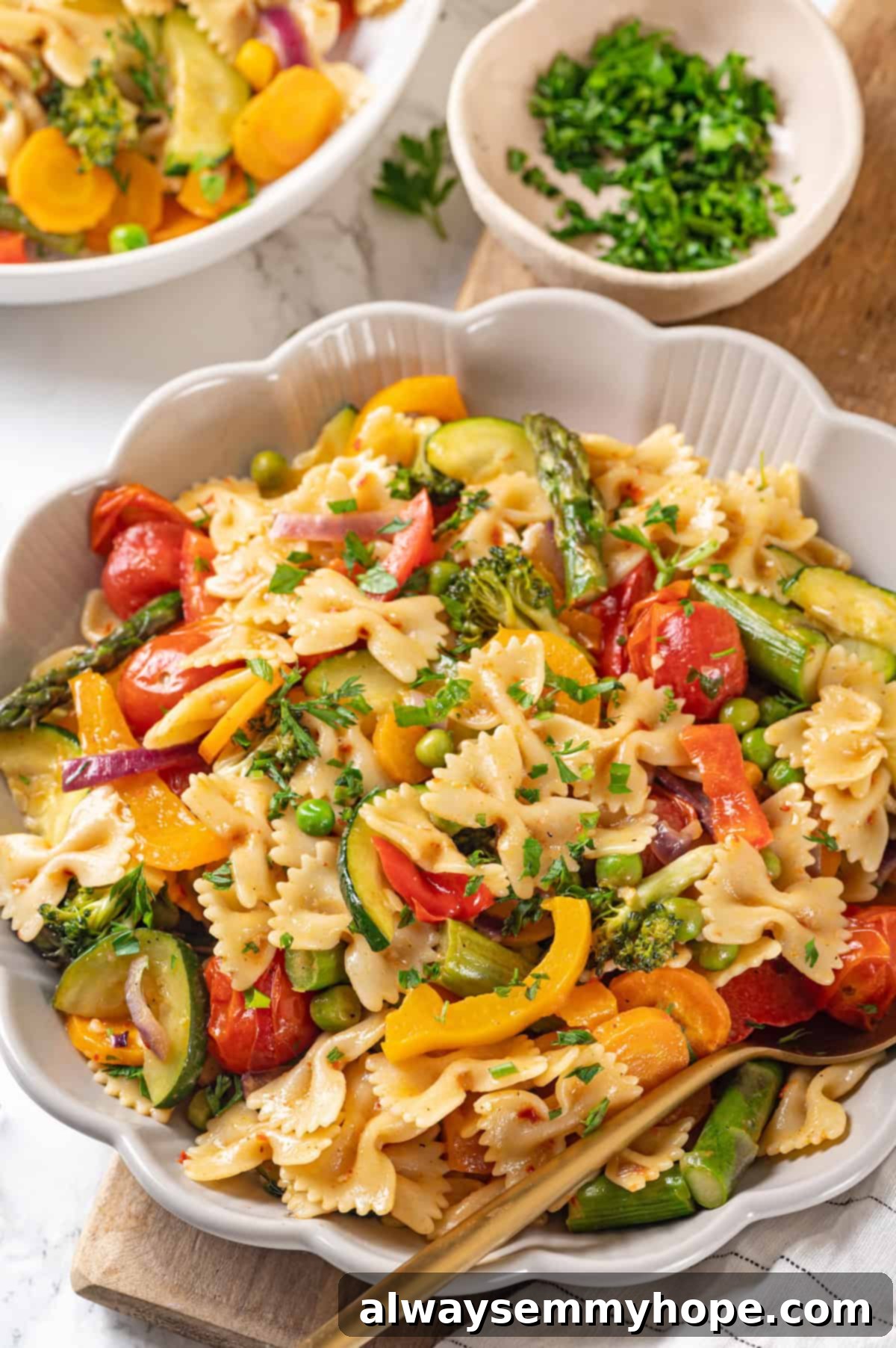 A close-up shot of a bowl of vegan pasta primavera with a serving spoon, showcasing its rich texture and colorful vegetables