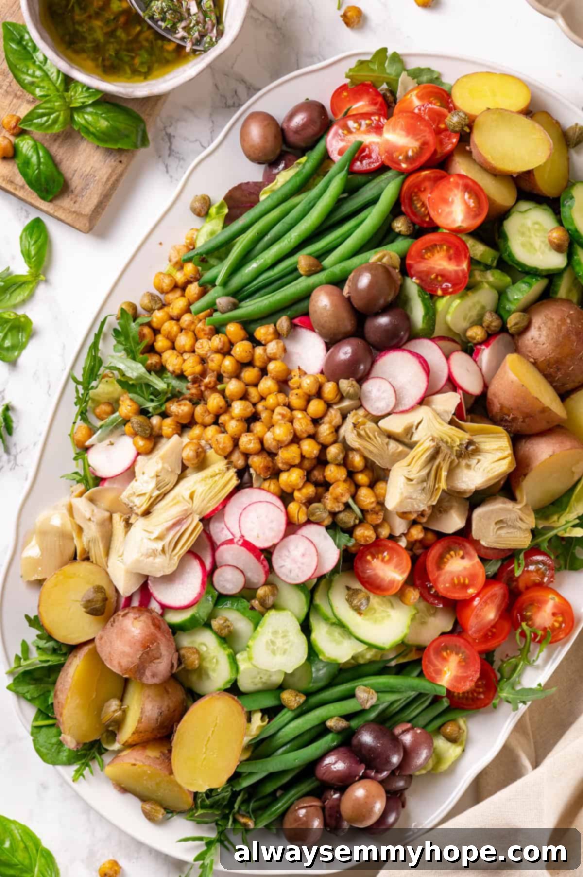 Overhead view of vibrant vegan Nicoise salad on a large serving platter, showcasing colorful vegetables and crispy chickpeas.