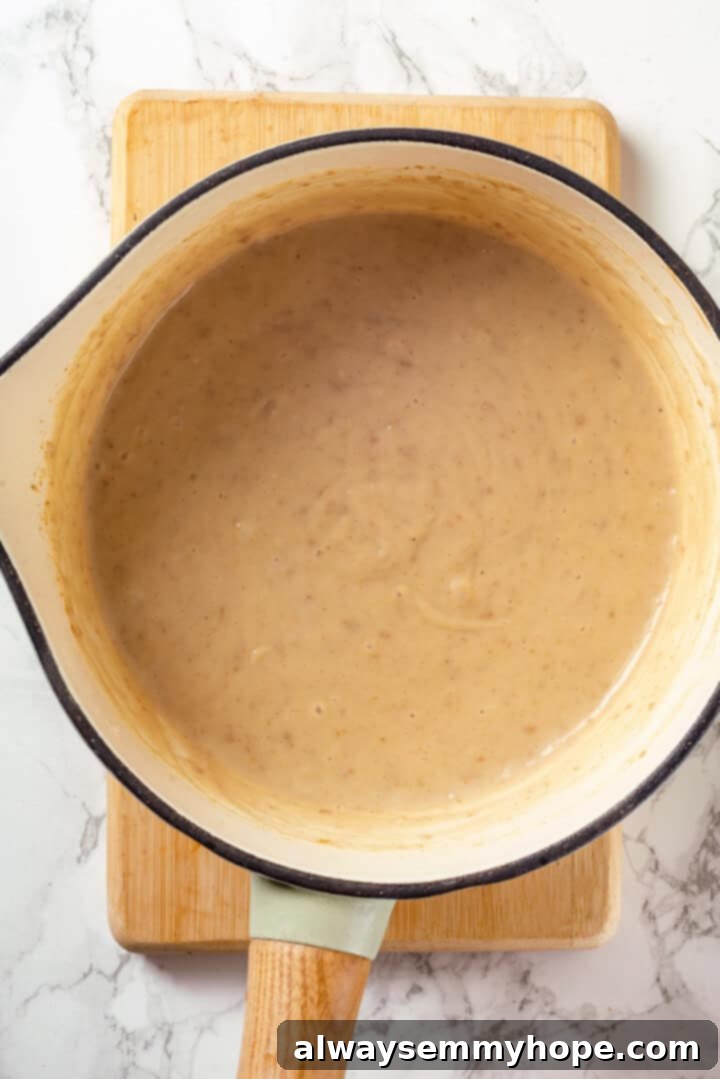 This vegan moussaka recipe has all the flavour of the classic Greek eggplant dish, but with tender lentils and mushrooms replacing the meat! Overhead view of bechamel sauce in pan