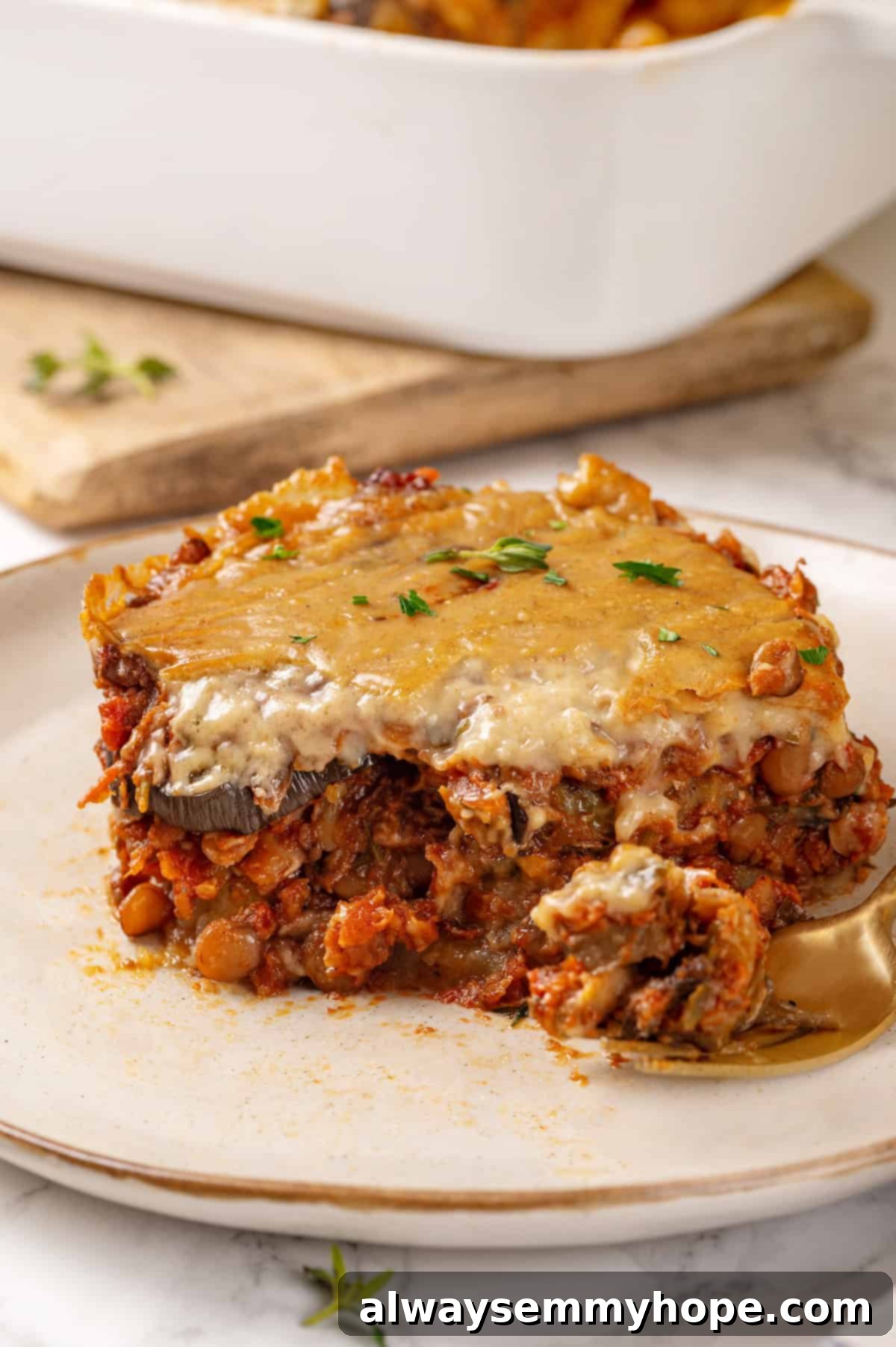 This vegan moussaka recipe has all the flavour of the classic Greek eggplant dish, but with tender lentils and mushrooms replacing the meat! Portion of vegan moussaka with lentils on plate