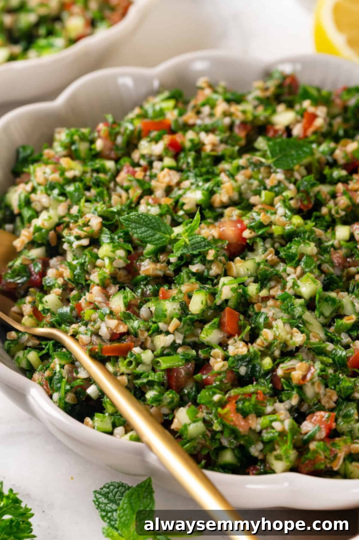 Bowl of tabbouleh with spoon, showcasing its fresh parsley, mint, tomatoes, cucumbers, and bulgur