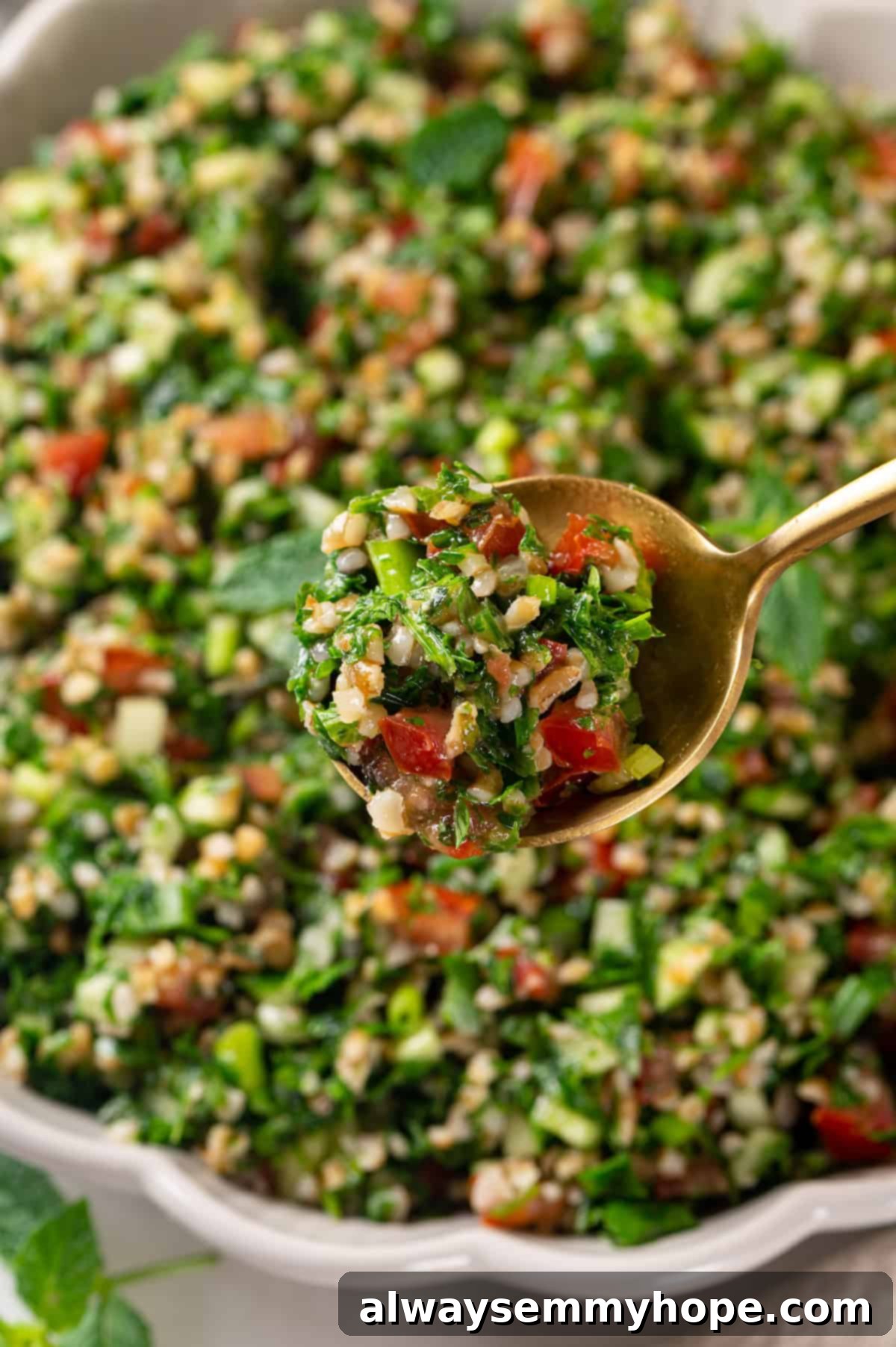 Spoonful of tabbouleh salad held over bowl, showing the texture and freshness of the ingredients
