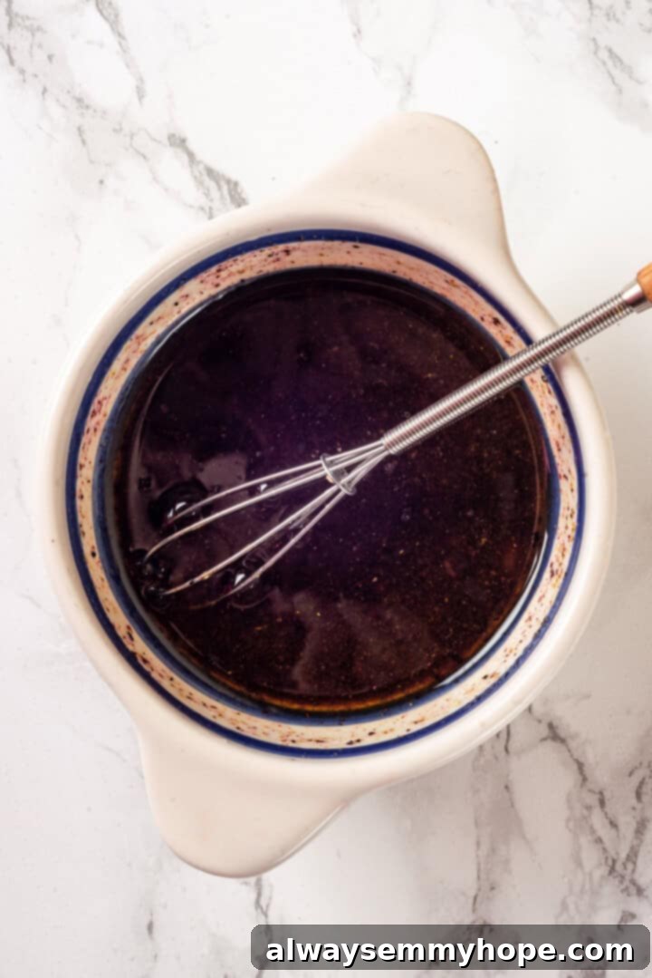 The vibrant lemon-sumac dressing, perfectly emulsified, in a small bowl with a whisk. Bowl of freshly whisked dressing for fattoush salad with a whisk