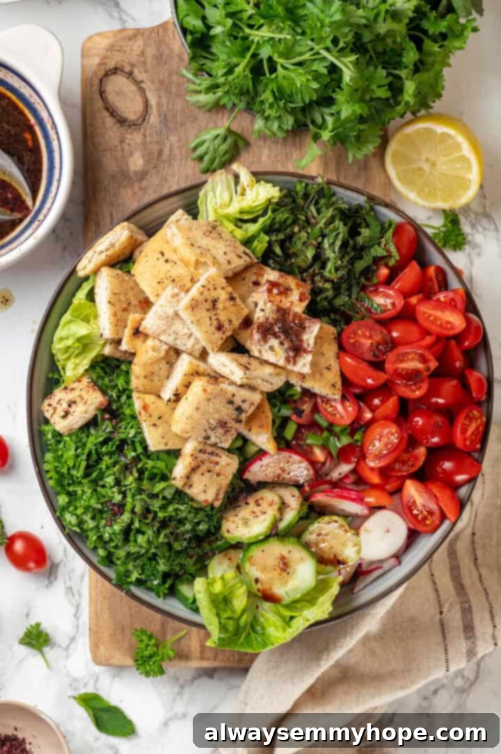 A large bowl filled with an assortment of crisp vegetables and fresh herbs, ready for the dressing. Overhead view of fresh ingredients for fattoush salad in a large bowl, pre-dressing