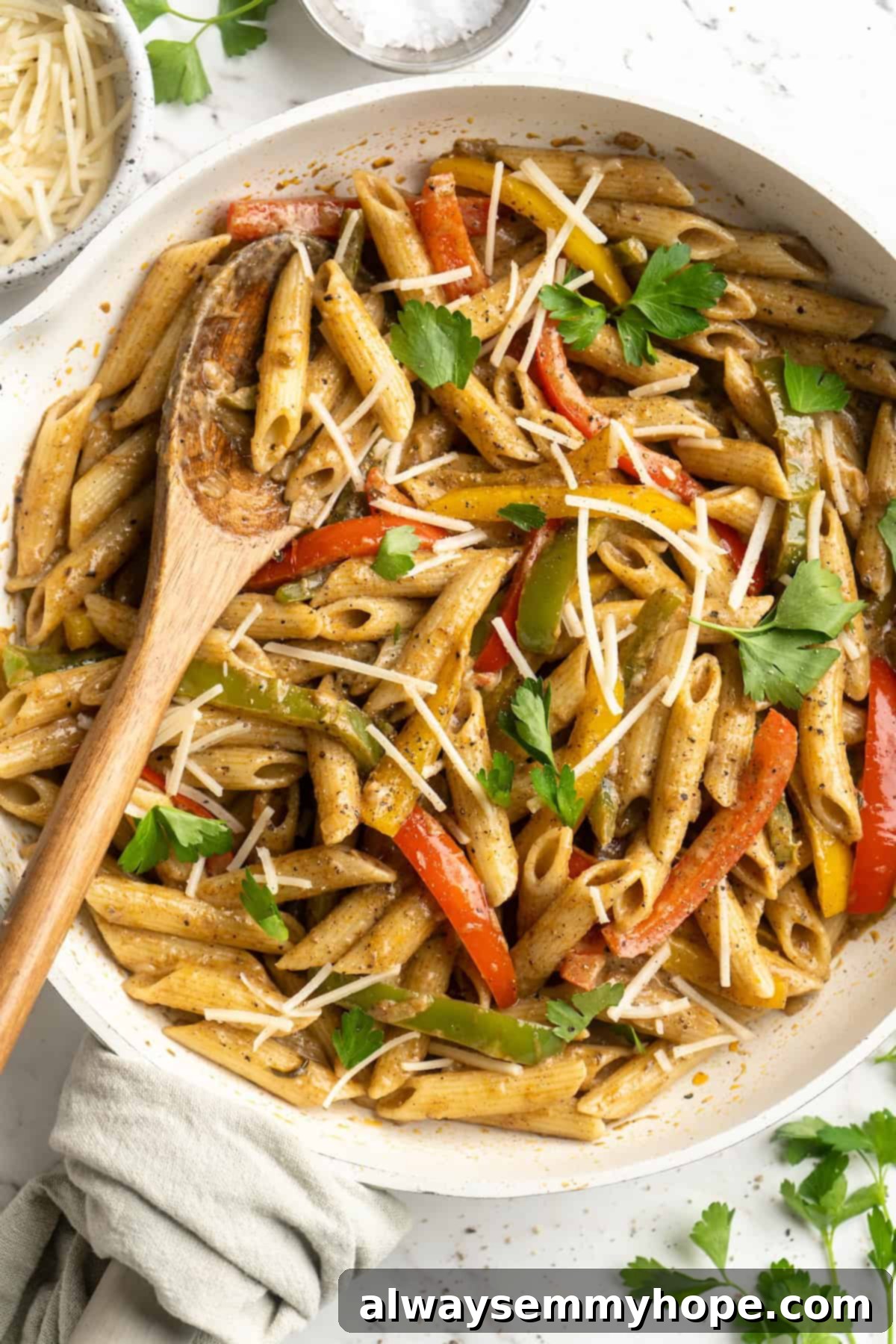 Overhead view of Rasta Pasta in a skillet with a wooden serving spoon, ready to be dished out.