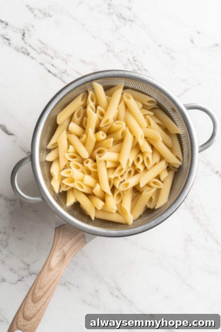 Overhead view of perfectly cooked penne pasta draining in a colander.