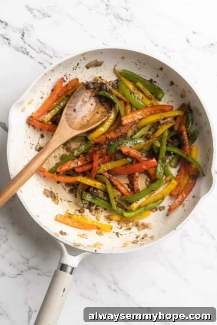 Overhead view of bell peppers combined with jerk seasoning and minced garlic in a skillet.