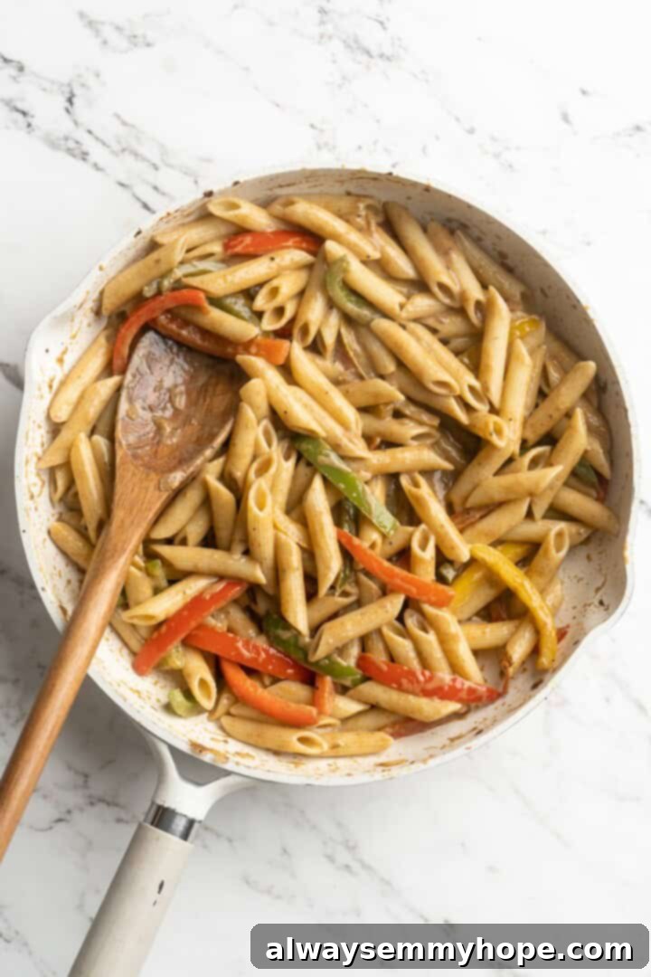 Overhead view of the creamy Rasta Pasta sauce simmering in the skillet with bell peppers.