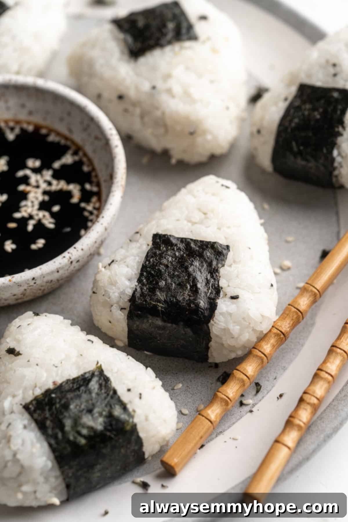 A vibrant plate of freshly prepared homemade vegan onigiri, expertly shaped and wrapped in nori, served with a small side of dipping sauce, showcasing a delicious and healthy snack or meal.
