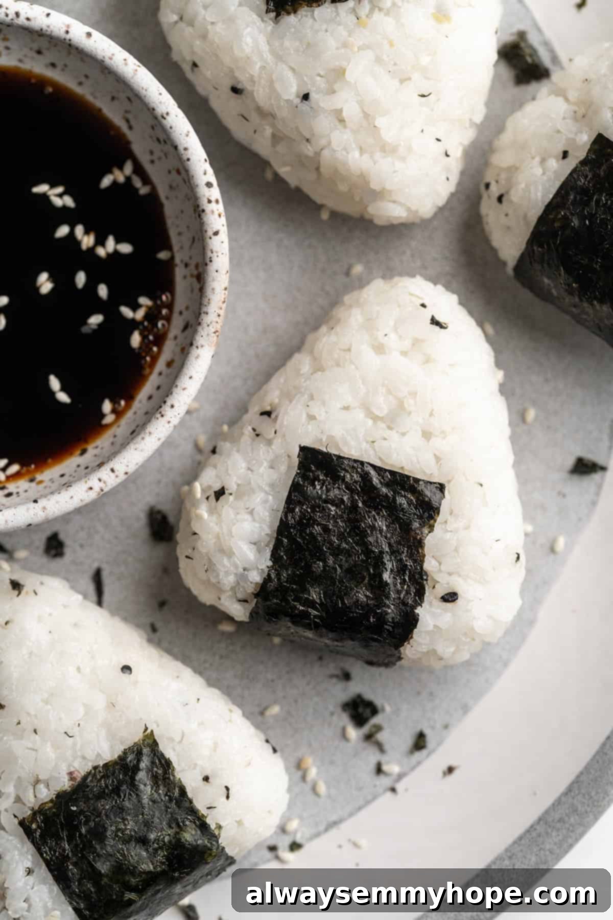 A close-up shot of several perfectly crafted homemade vegan onigiri on a plate, featuring their distinct shapes and nori wrappers, ready to be enjoyed as a delightful Japanese snack.