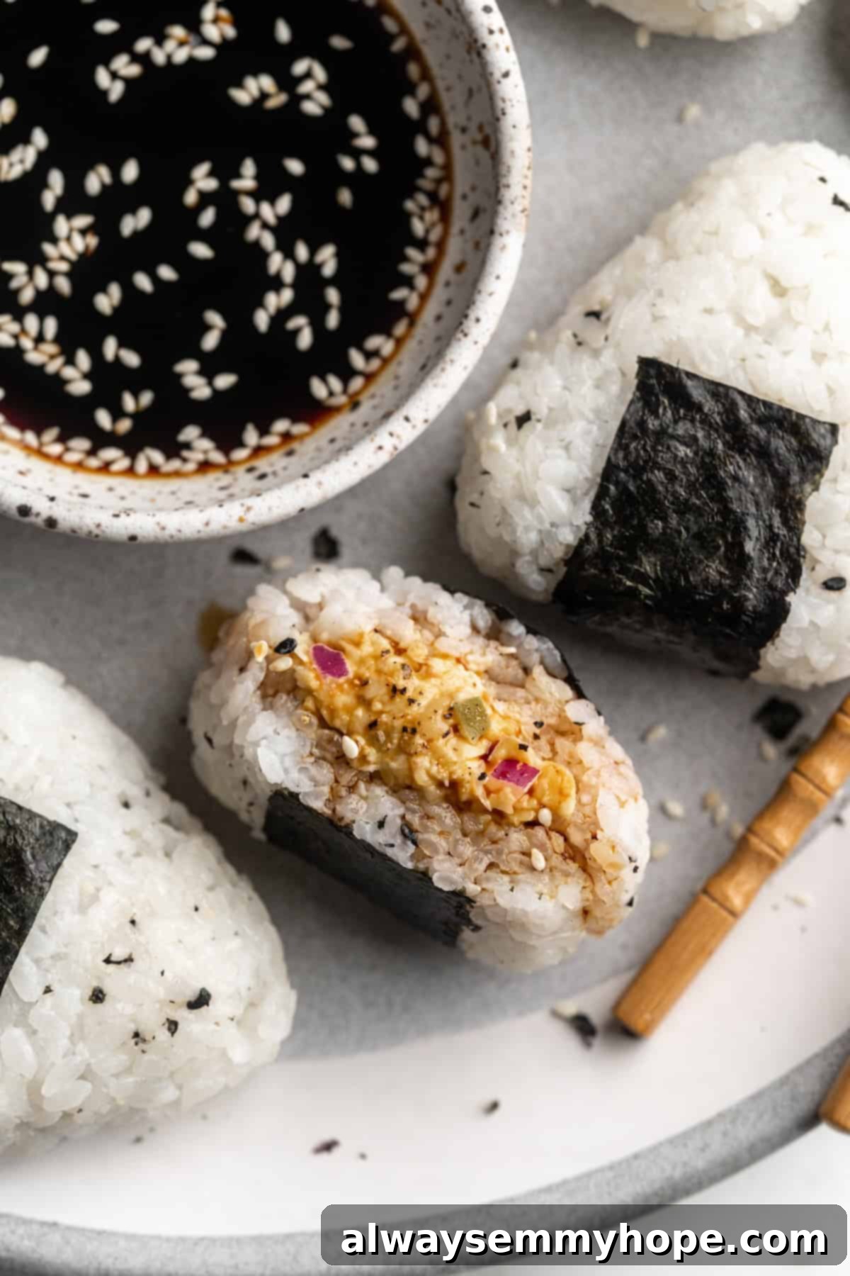A close-up of a single, perfectly formed vegan onigiri, revealing its chickpea tuna filling and the well-seasoned sushi rice, ready for a delicious bite.