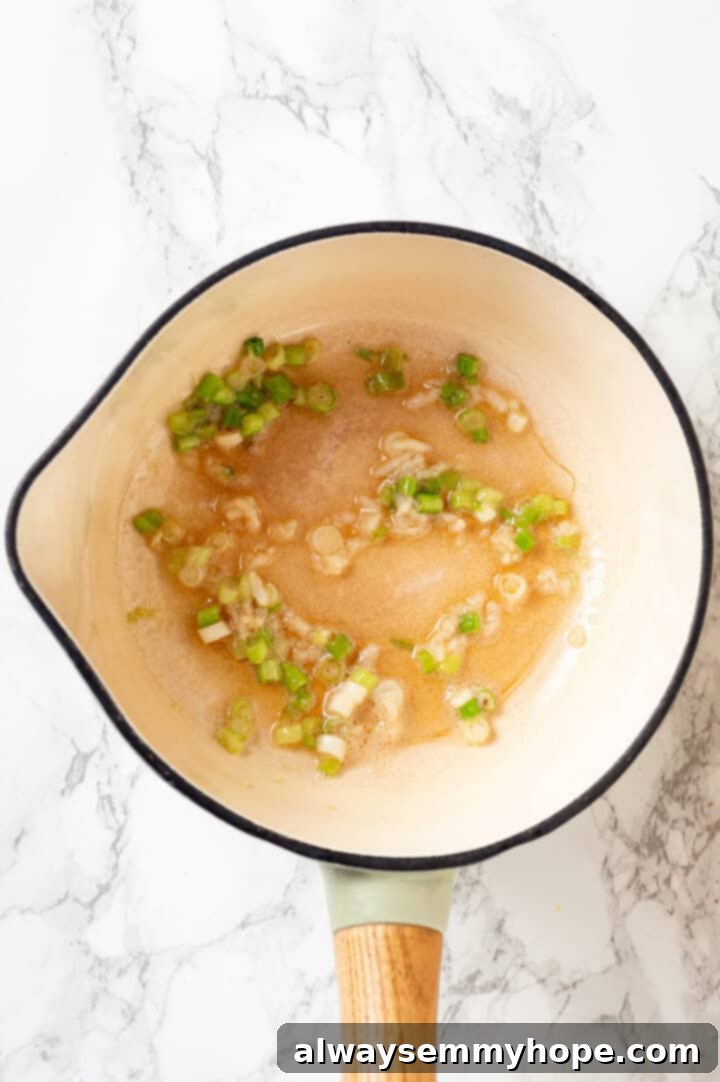This spicy ramen recipe is an easy budget-friendly dinner that's packed with flavour! Sweet, spicy and umami—and it takes minutes to make! Overhead view of scallion whites cooking in oil