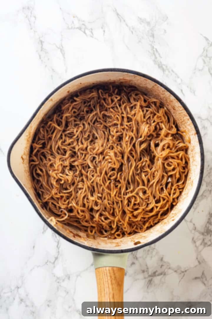 This spicy ramen recipe is an easy budget-friendly dinner that's packed with flavour! Sweet, spicy and umami—and it takes minutes to make! Overhead view of spicy ramen in pan