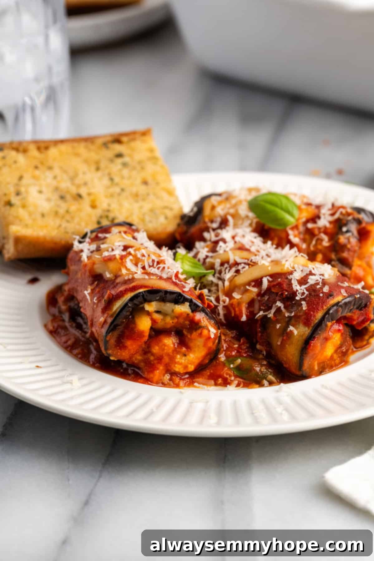 Side view of vegan eggplant rollatini on plate with garlic bread