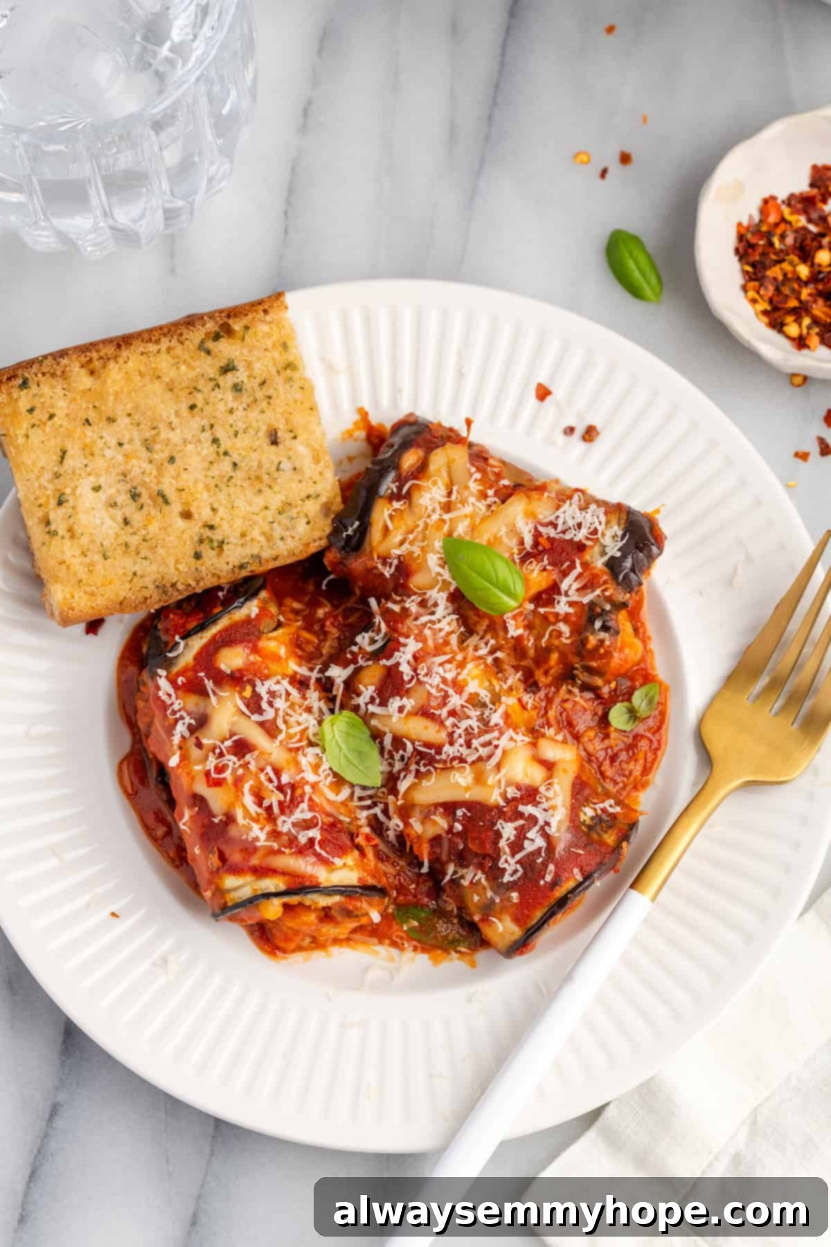 Overhead view of vegan eggplant rollatini on plate with garlic bread