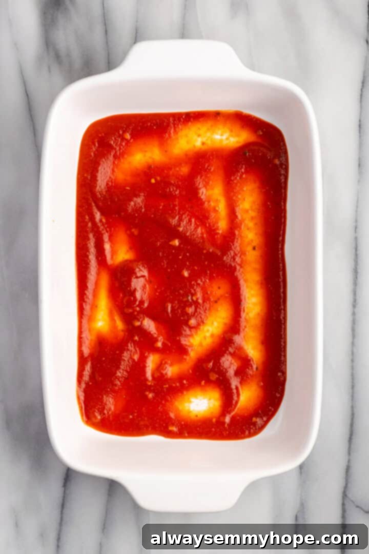 Overhead view of tomato sauce in bottom of casserole dish