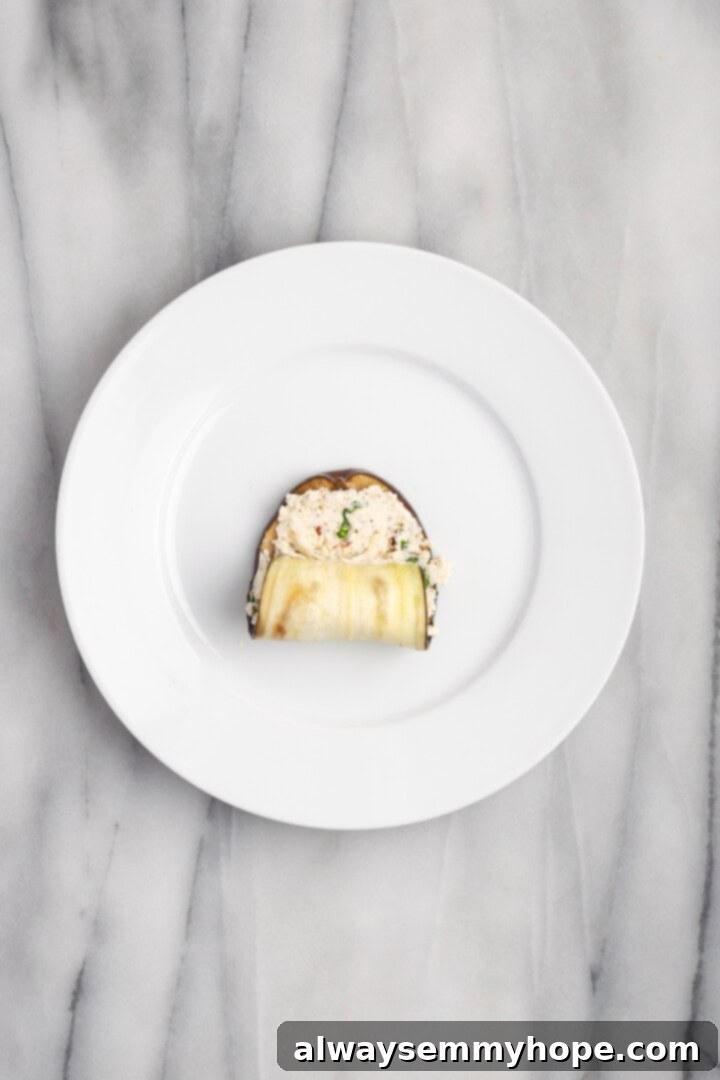 Rolling up cheese filling into roasted eggplant