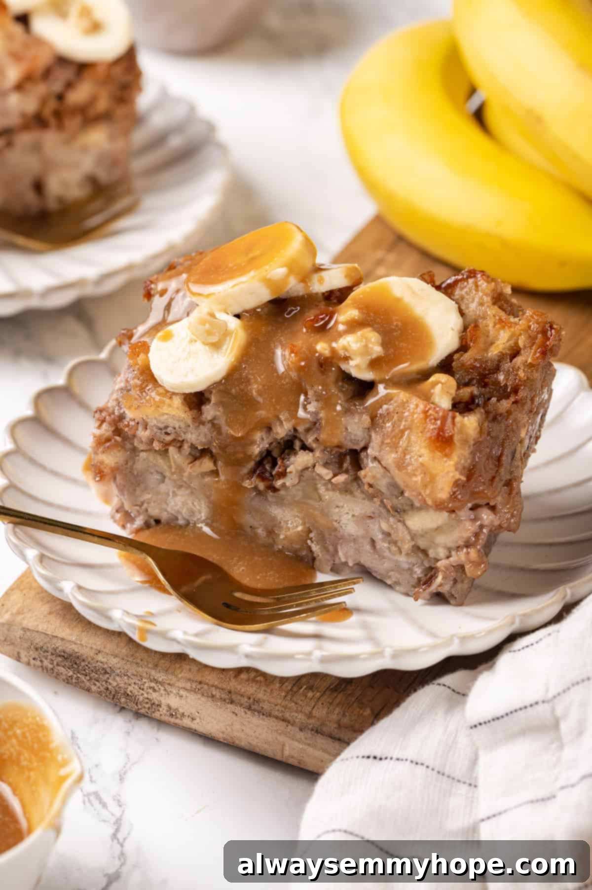 A slice of caramel-topped banana bread pudding served on a plate with a fork, ready to be enjoyed.