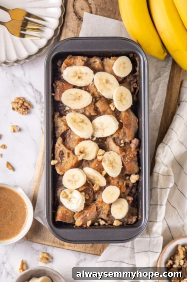 Overhead view of the baked banana bread pudding in a loaf pan, garnished with fresh banana slices, ready to be served.