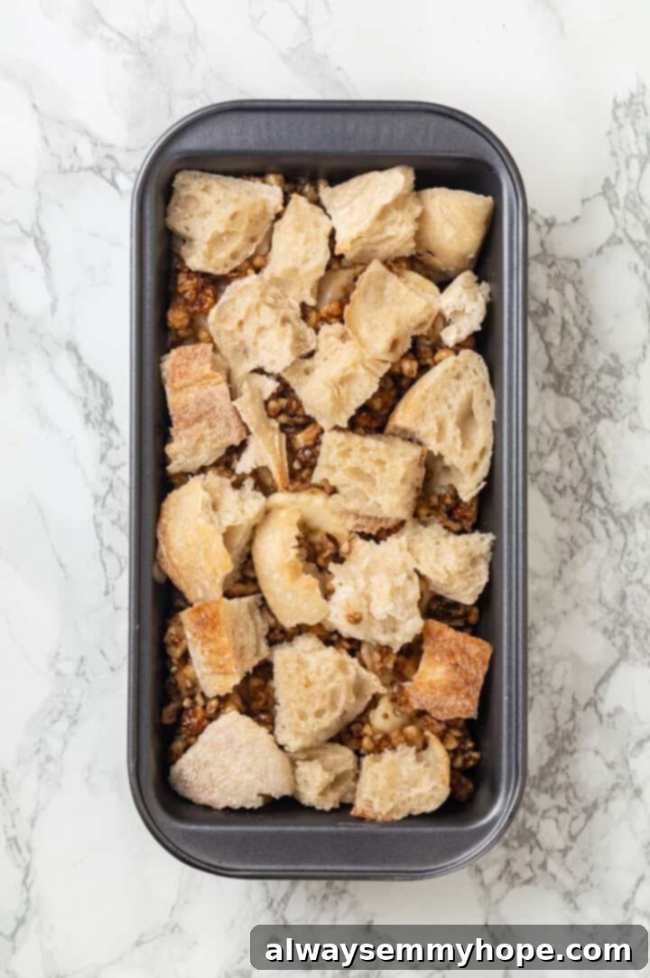 Overhead view of banana bread pudding assembled in a pan, before the final layer of custard is added, showing the distinct layers.