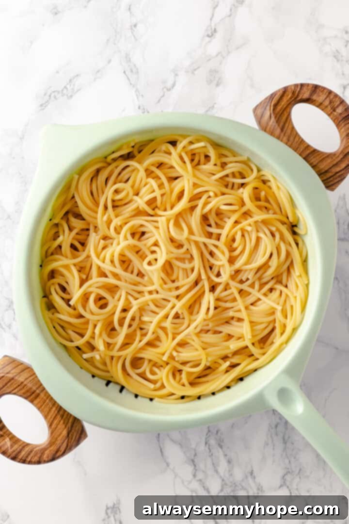 This creamy vegan pasta carbonara is a delicious plant-based alternative to the traditional recipe with mushrooms standing in for the meat! Overhead view of cooked spaghetti in strainer