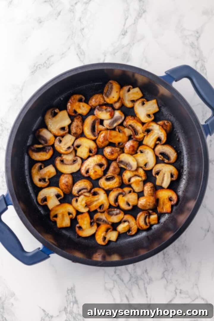 This creamy vegan pasta carbonara is a delicious plant-based alternative to the traditional recipe with mushrooms standing in for the meat! Overhead view of sauteed mushrooms in skillet