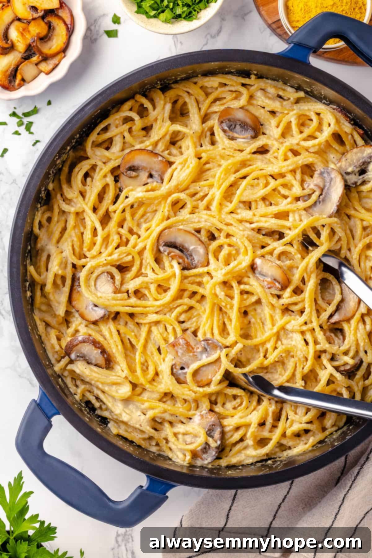 This creamy vegan pasta carbonara is a delicious plant-based alternative to the traditional recipe with mushrooms standing in for the meat! Overhead view of vegan pasta carbonara in pan with tongs