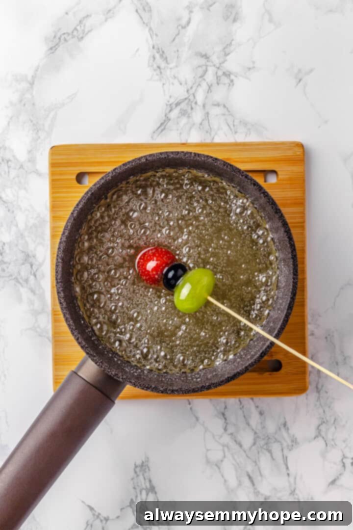 Tanghulu is one part fruit, one part candy and entirely delicious! Fruit skewers dipped in candy coating to create a sweet, crunchy shell. Dipping fruit skewer into sugar mixture