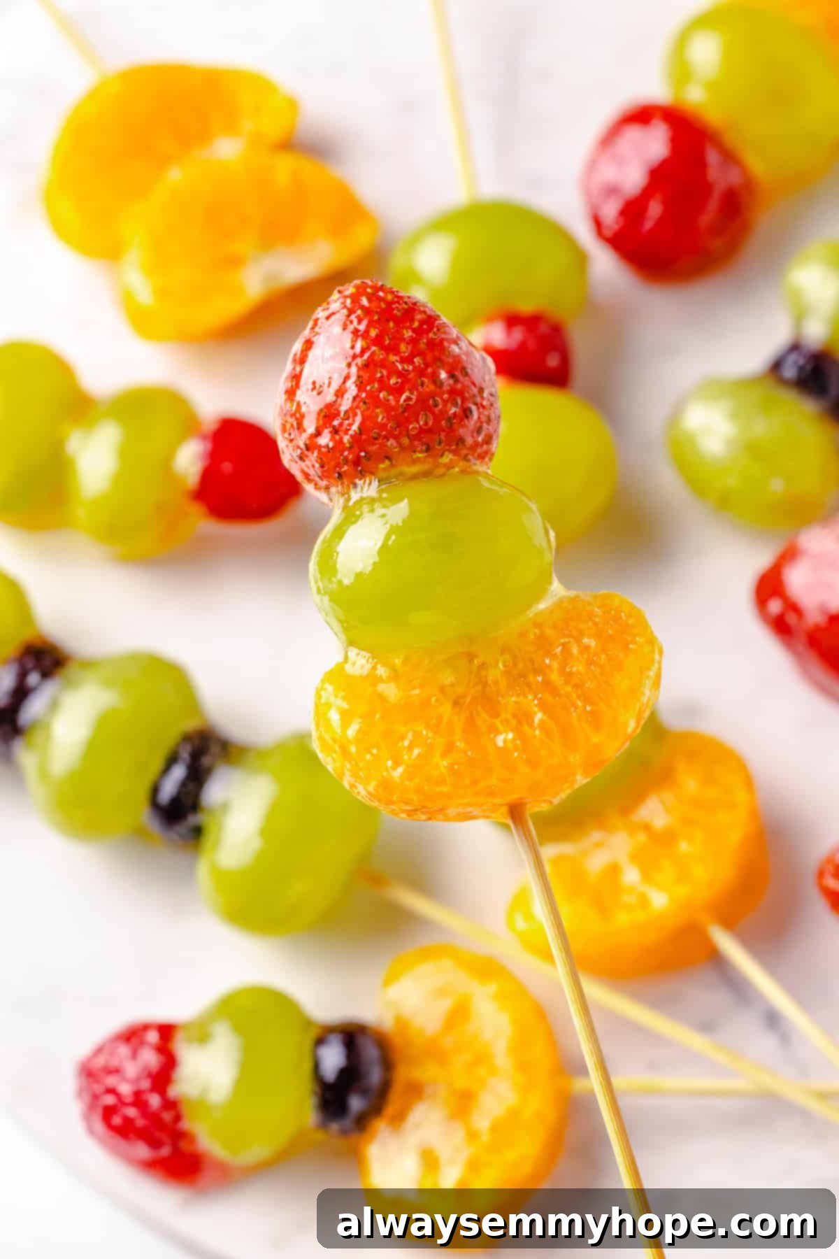 Tanghulu is one part fruit, one part candy and entirely delicious! Fruit skewers dipped in candy coating to create a sweet, crunchy shell. Holding tanghulu skewer over marble board