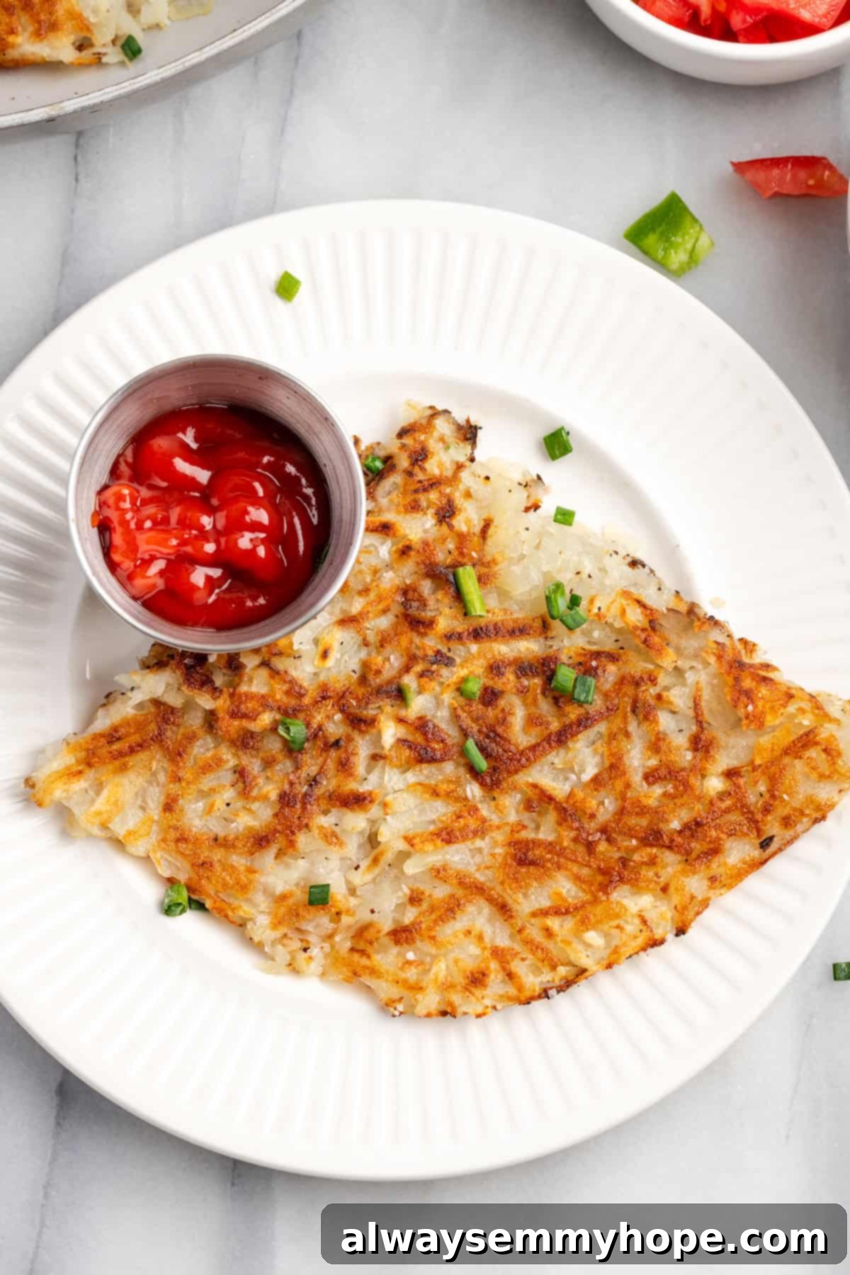 A plate of golden-brown, perfectly crispy hash browns, served with a side of ketchup for dipping.