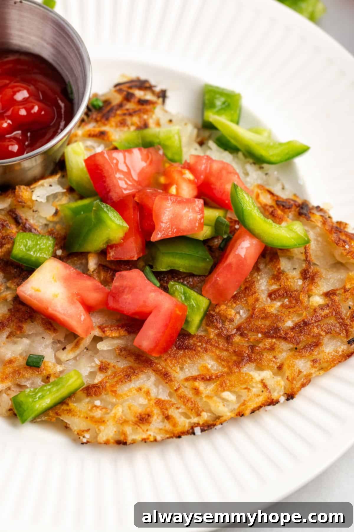 A plate of perfectly crispy hash browns topped with fresh herbs and bell pepper, showcasing a serving suggestion.