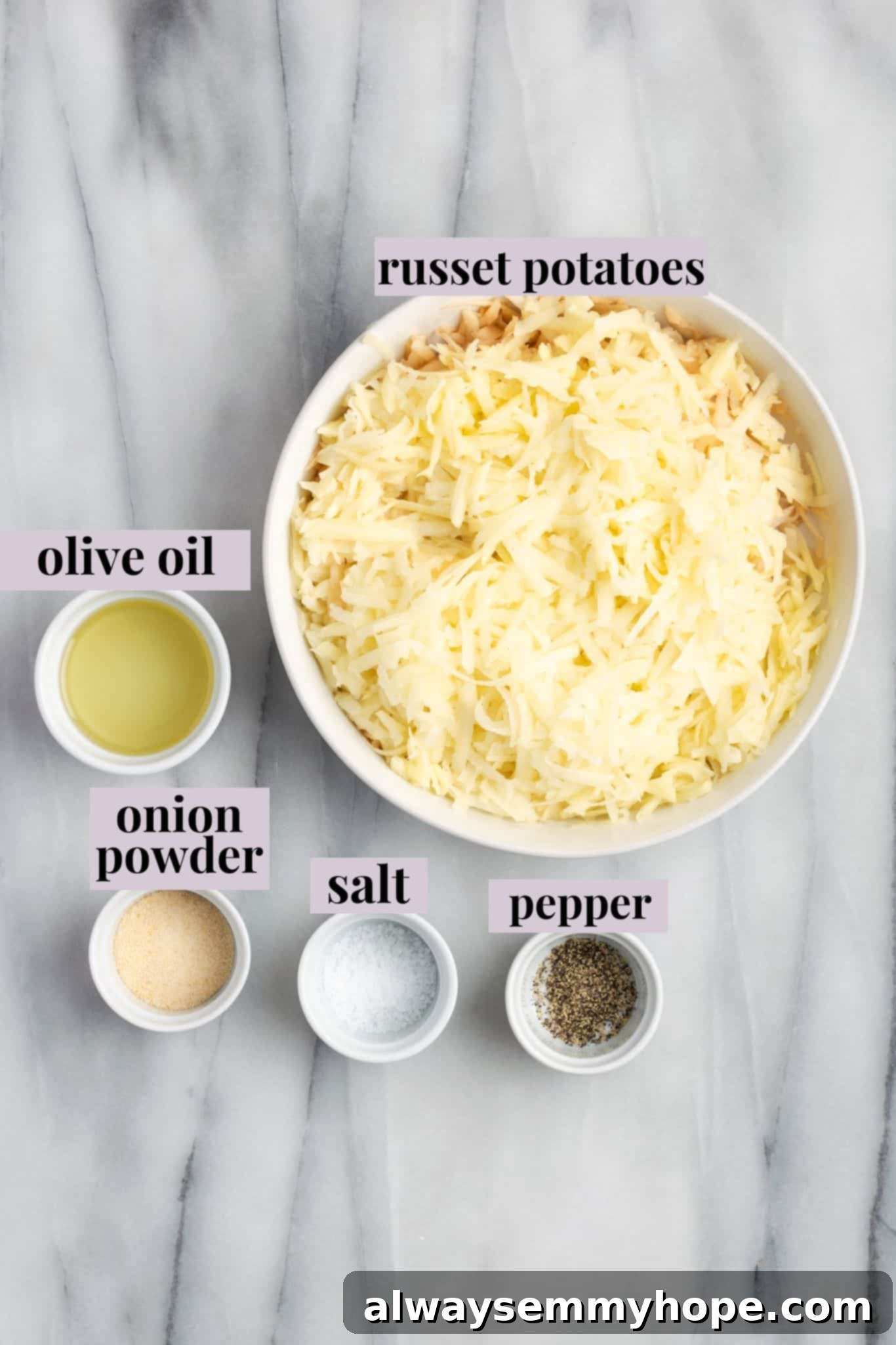 Overhead view of fresh russet potatoes, a bottle of olive oil, onion powder, salt, and pepper, neatly arranged as ingredients for hash browns.