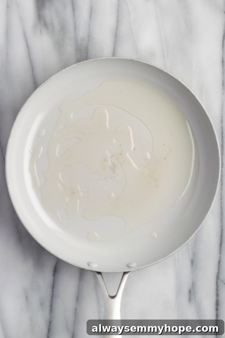Overhead view of olive oil shimmering in a hot skillet, ready for the potatoes.