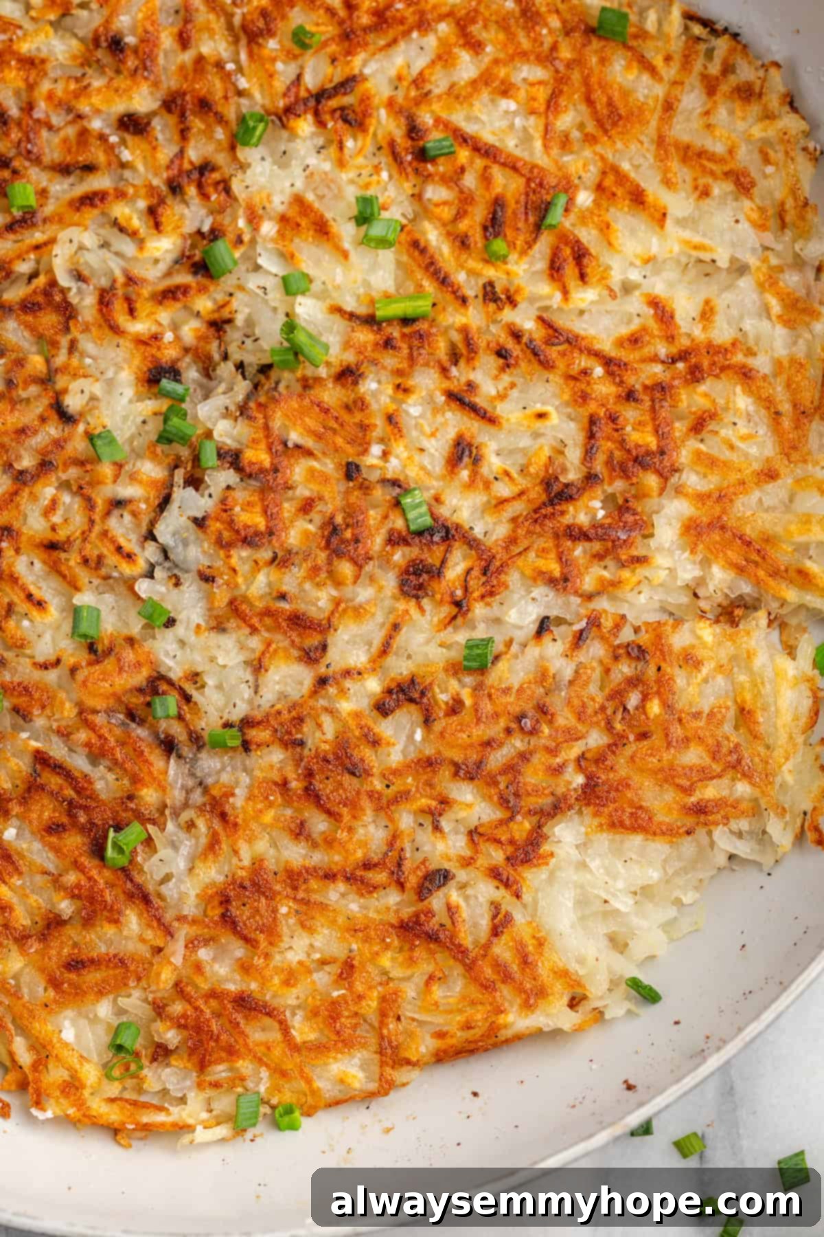 A close-up of golden-brown homemade hash browns cooking in a skillet, showcasing their appealing crispy texture.