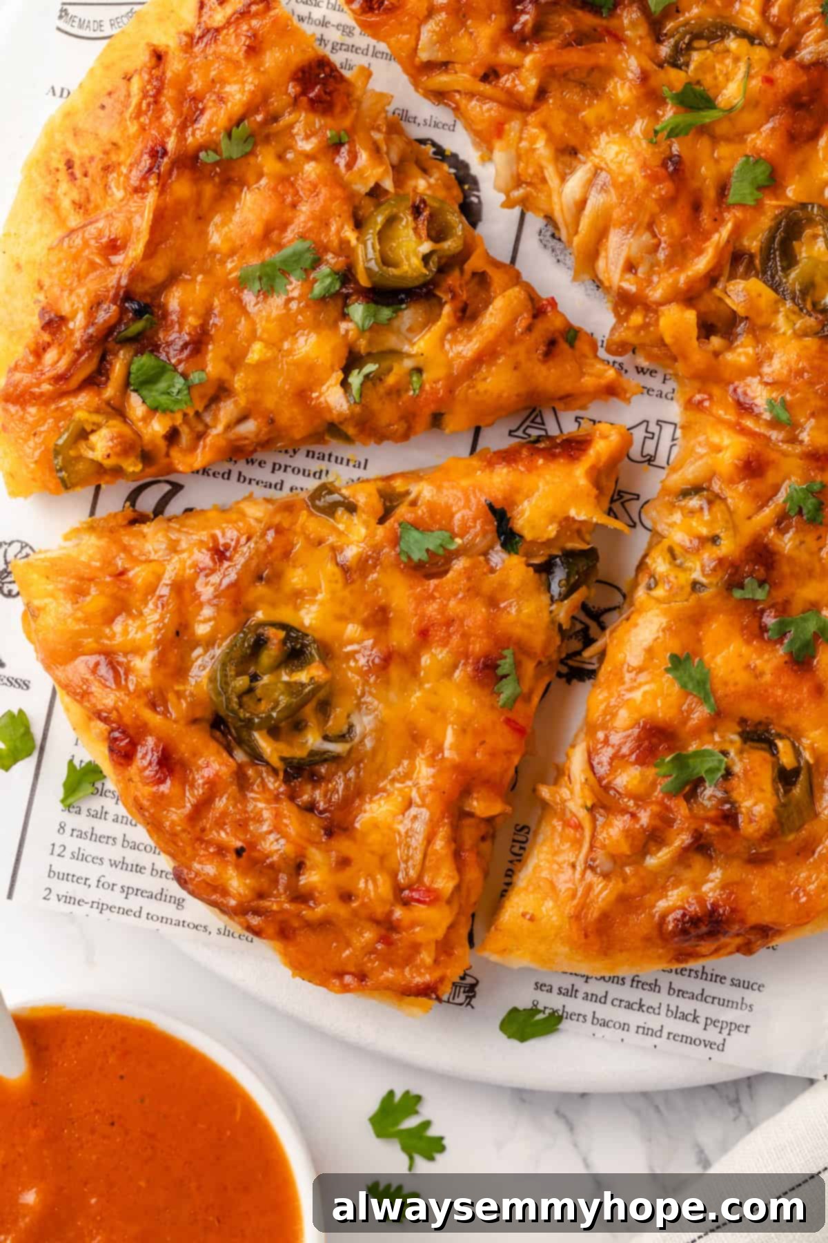 This vegan birria pizza recipe has all the savory, spicy goodness and toppings of birria tacos, but in the form of a cheesy pizza! Overhead view of sliced vegan birria pizza on a marble board, garnished with cilantro and lime wedges