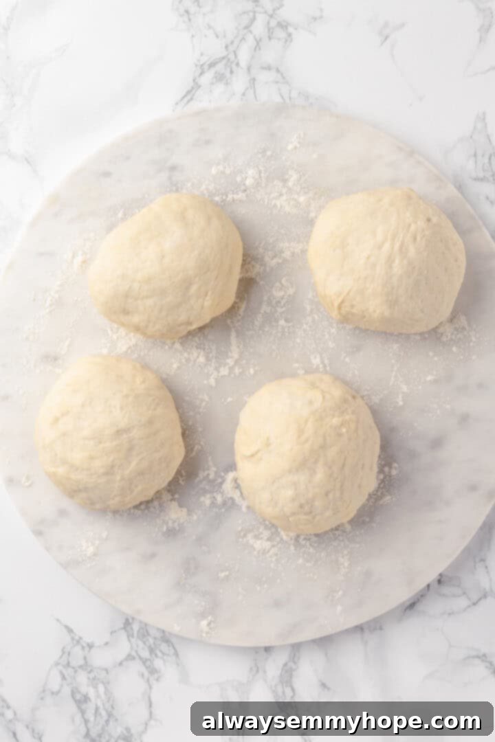This vegan birria pizza recipe has all the savory, spicy goodness and toppings of birria tacos, but in the form of a cheesy pizza! Overhead view of four neatly divided balls of pizza dough on a floured wooden surface
