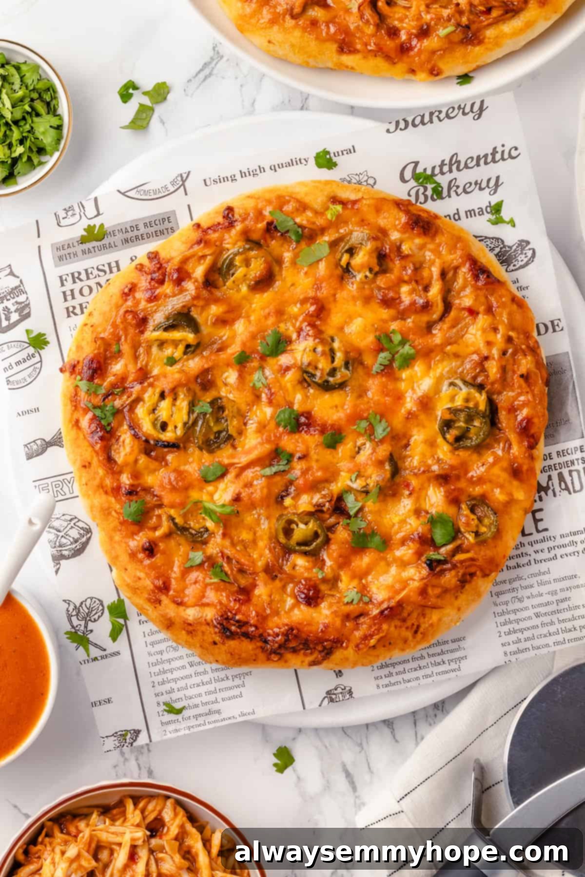 This vegan birria pizza recipe has all the savory, spicy goodness and toppings of birria tacos, but in the form of a cheesy pizza! Overhead view of an unsliced, baked vegan birria pizza on a light tabletop, ready to be cut