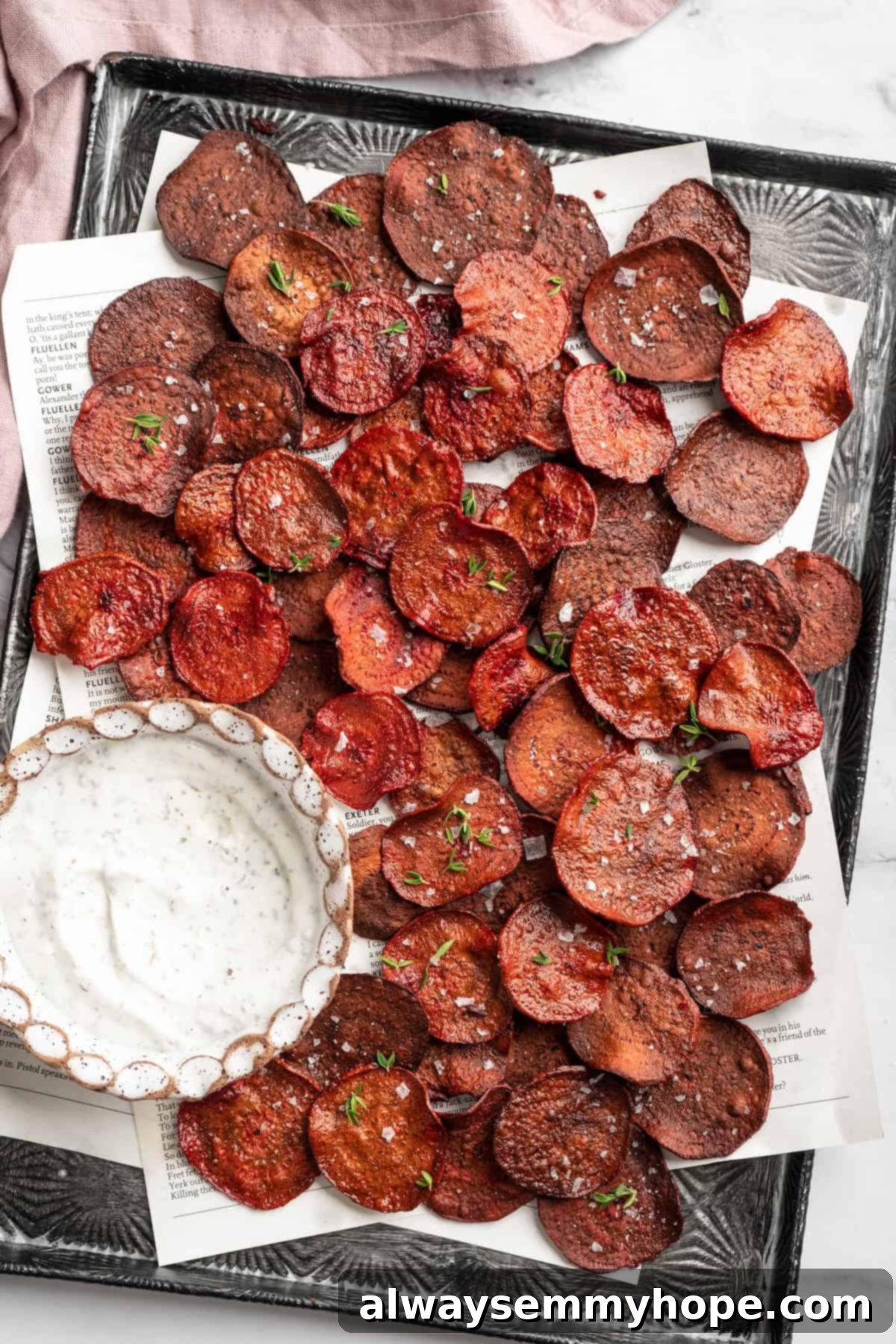 Overhead view of beet chips on sheet pan with bowl of dip