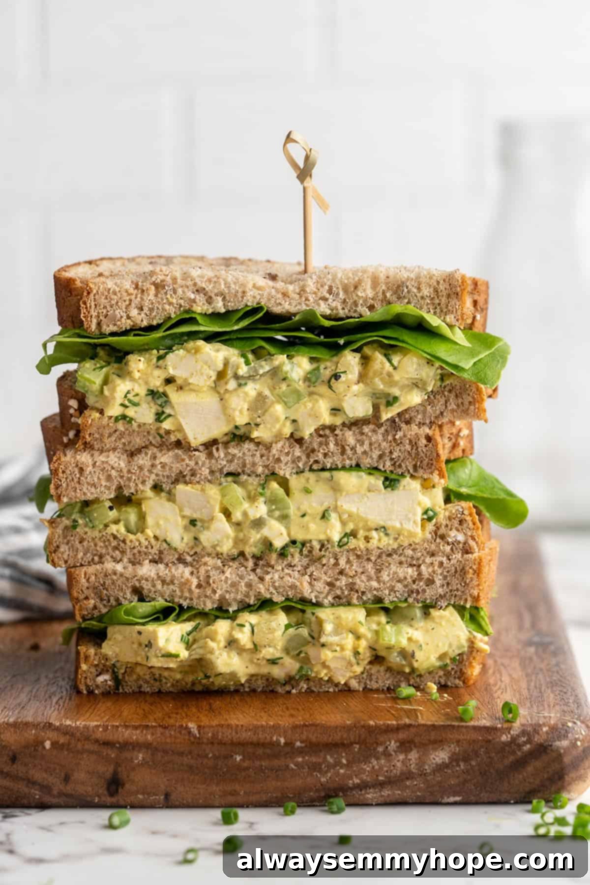 3 stacked tofu egg salad sandwiches on cutting board