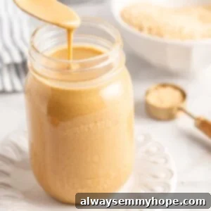 Simple Two Ingredient Tahini 2 Spoon of tahini held over jar