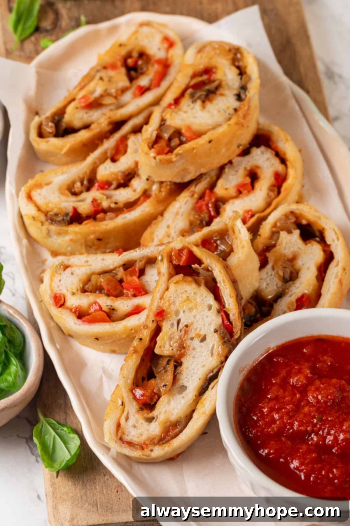 This vegan stromboli recipe is like a giant pizza roll, with marinara, plant-based cheese and veggies baked inside a golden brown crust. Yum! Stromboli slices on platter with marinara sauce