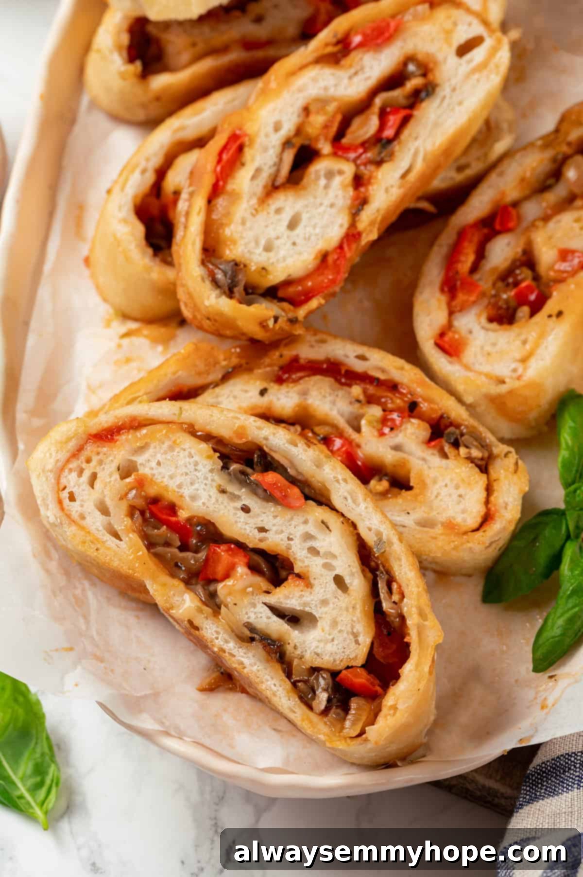 This vegan stromboli recipe is like a giant pizza roll, with marinara, plant-based cheese and veggies baked inside a golden brown crust. Yum! Vegan stromboli slices stacked on platter