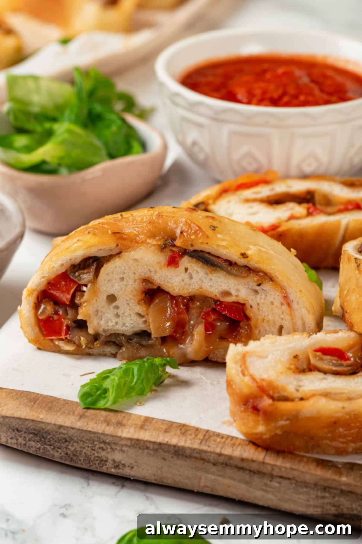 This vegan stromboli recipe is like a giant pizza roll, with marinara, plant-based cheese and veggies baked inside a golden brown crust. Yum! Sliced stromboli on wooden board with bowl of marinara