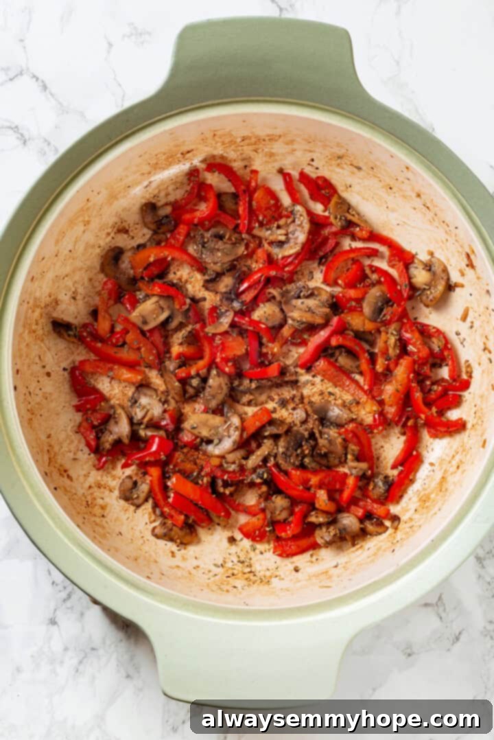 This vegan stromboli recipe is like a giant pizza roll, with marinara, plant-based cheese and veggies baked inside a golden brown crust. Yum! Overhead view of cooked peppers and mushrooms with garlic