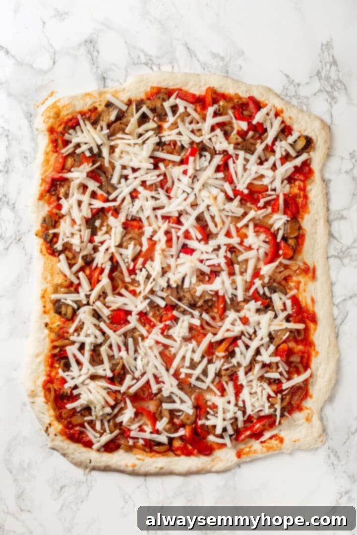 This vegan stromboli recipe is like a giant pizza roll, with marinara, plant-based cheese and veggies baked inside a golden brown crust. Yum! Pizza dough topped with marinara, veggies, and cheese for stromboli recipe