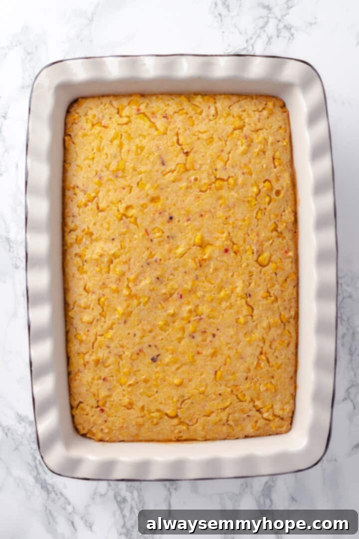This easy vegan corn casserole is creamy, cheesy and sweet, with all the flavour you love of the holiday classic. Always a crowd-plaser! Overhead view of a baked vegan corn casserole, golden brown and slightly puffed, before the addition of vegan cheese for the final bake.