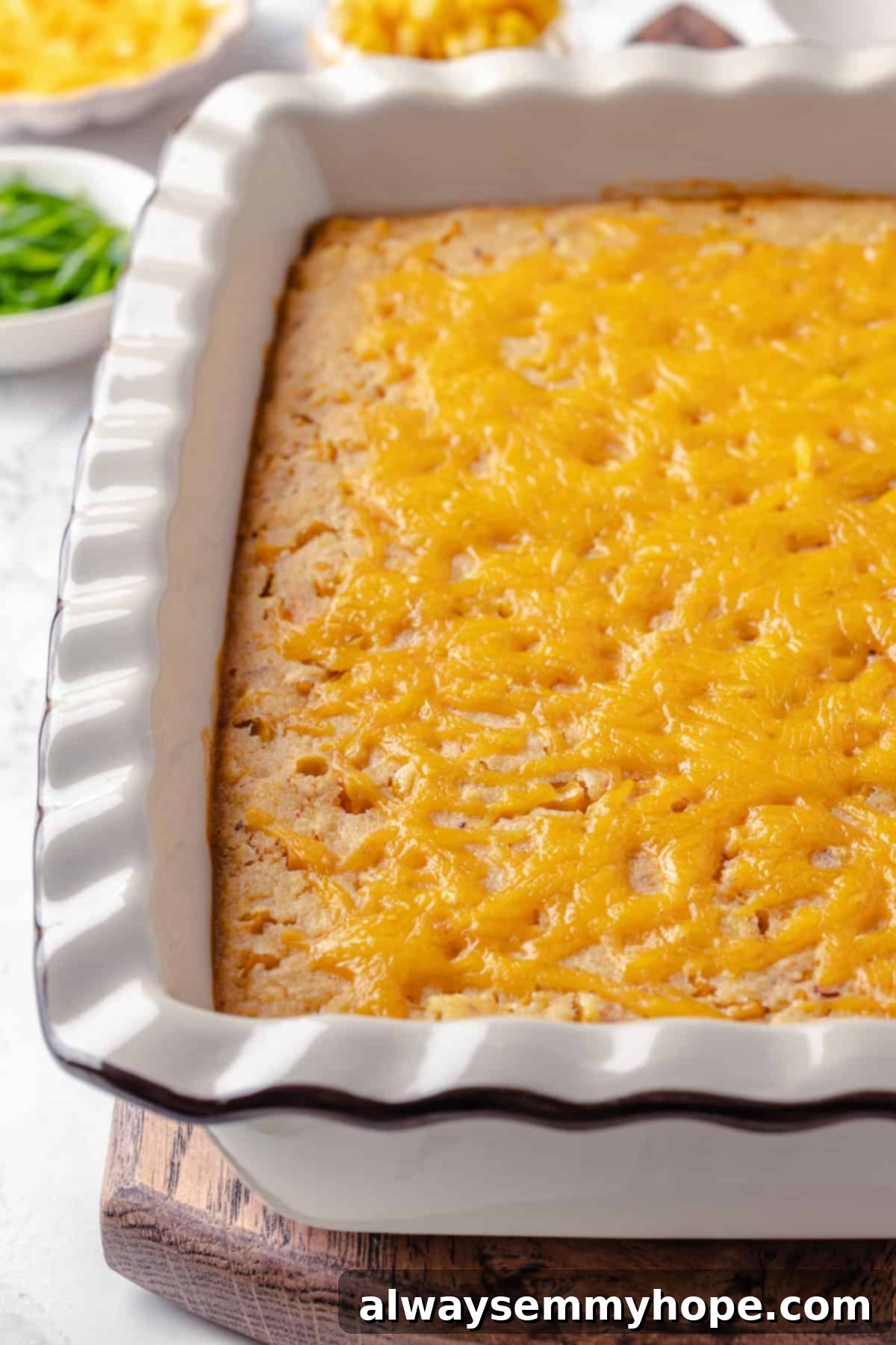 This easy vegan corn casserole is creamy, cheesy and sweet, with all the flavour you love of the holiday classic. Always a crowd-pleaser! A freshly baked vegan corn casserole, golden brown with melted vegan cheese, resting in a glass baking dish, ready to be served.
