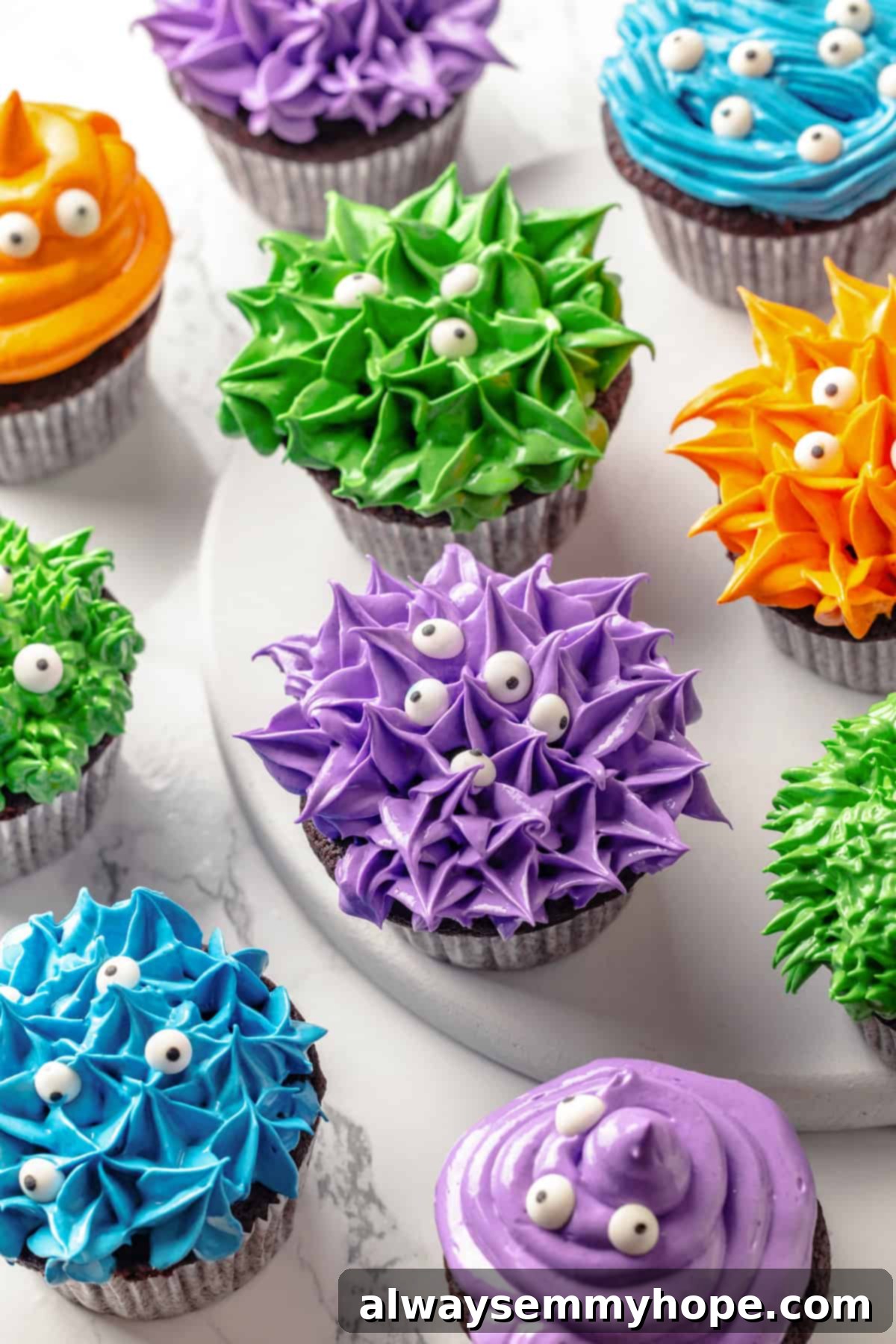 These moist chocolate Halloween cupcakes are topped with cute frosting monsters in a variety of colours. They taste as good as they look! A vibrant assortment of multicoloured Halloween monster cupcakes with furry frosting and candy eyes, arranged appealingly for a festive display.