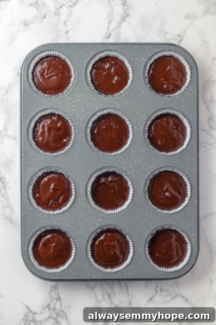 These moist chocolate Halloween cupcakes are topped with cute frosting monsters in a variety of colours. They taste as good as they look! Overhead view of unbaked vegan chocolate cupcake batter neatly poured into cupcake liners in a muffin pan, ready for baking.