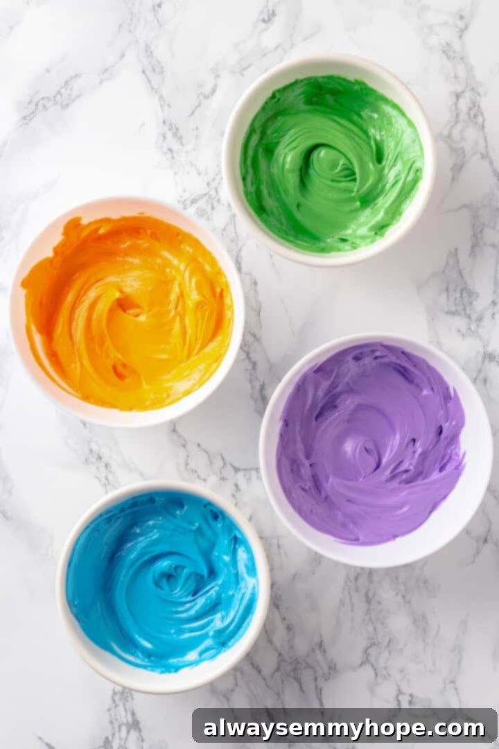 These moist chocolate Halloween cupcakes are topped with cute frosting monsters in a variety of colours. They taste as good as they look! Overhead view of vibrant orange, green, purple, and blue vegan buttercream frostings in separate bowls, colored and ready for piping onto Halloween monster cupcakes.